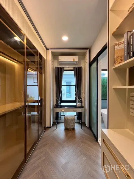 Detached House for rent or sale in Saphan Sung, Bangkok - Compact home office corridor with built-in shelving, glass wardrobe and a window desk.