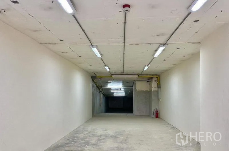 Retail Space for rent in Watthana, Bangkok - Long rectangular retail interior with exposed ceiling lights and a fire extinguisher.