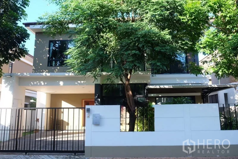 独立式住宅 出租在Bang Phli, Samut Prakan - 现代两层独栋别墅正面，带围栏车道与成树