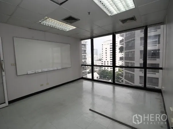 办公空间 出租在Watthana, Bangkok - 转角办公室，落地窗城市景观、白板与网格吊顶灯。