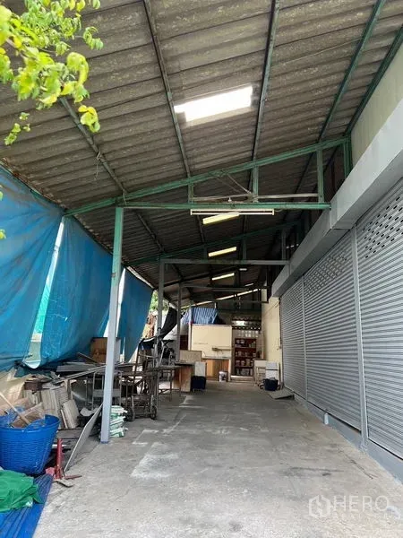 Warehouse for rent in Khlong Sam Wa, Bangkok - Covered loading and working bay with metal roof next to roller shutters.