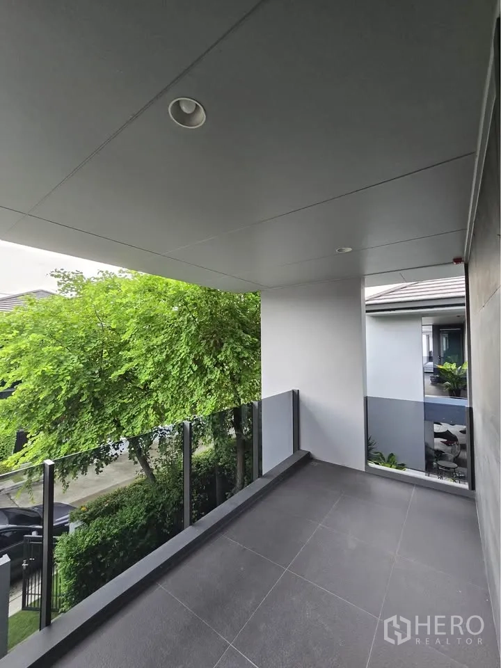 Detached House for rent in Bang Kapi, Bangkok - Covered balcony with glass railing overlooking trees.