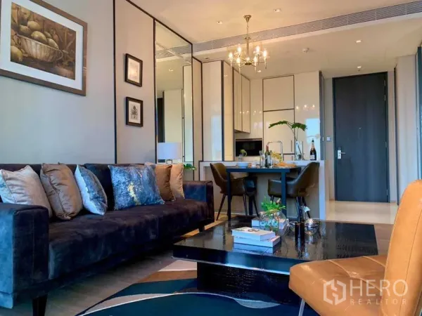 Condominium for rent in Khlong Toei, Bangkok - Elegant living and dining area with navy sofa, chandelier and open kitchen in a modern Bangkok condo.