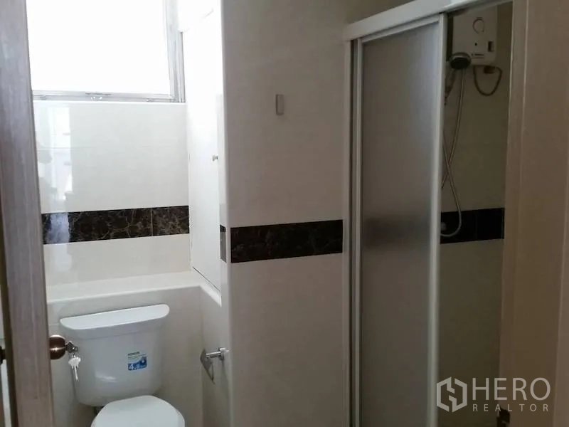 公寓 出租在Watthana, Bangkok - 紧凑浴室，坐便器与推拉门淋浴间。