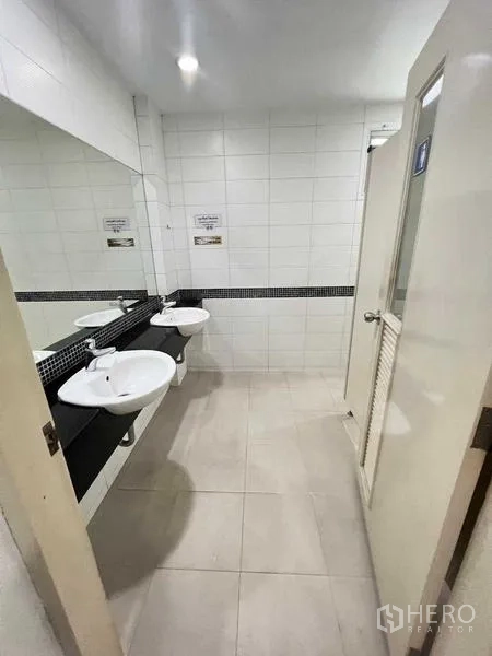 Office Space for rent in Wang Thonglang, Bangkok - Clean shared restroom with twin basins, a long mirror, and white tiled walls.