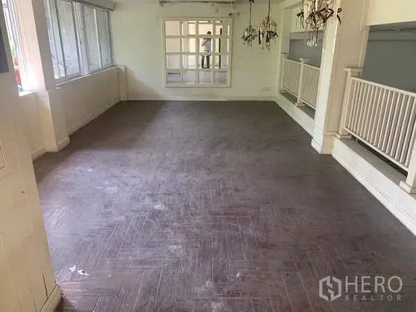 Shophouse for rent in Watthana, Bangkok - Sunlit upper floor with herringbone wood-look flooring, wide windows and white balustrade.