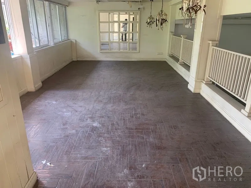 Shophouse for rent in Watthana, Bangkok - Sunlit upper floor with herringbone wood-look flooring, wide windows and white balustrade.