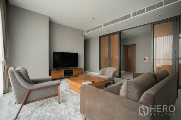Condominium for rent or sale in Watthana, Bangkok - Modern Thonglor condo living room with gray sofa set, TV console, coffee table and sliding glass partitions.