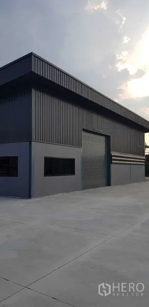 货栈 出租在Lat Lum Kaeo, Pathum Thani - 傍晚外观侧视，卷帘门与硬铺场地一览。