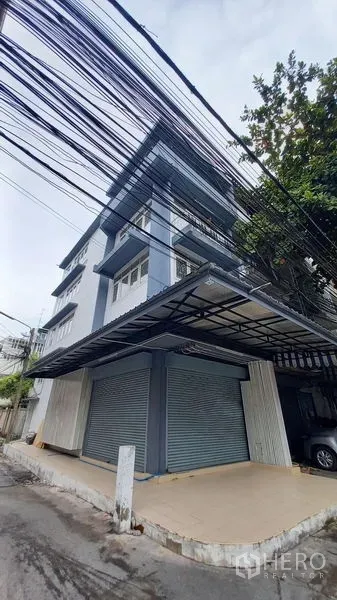 Shophouse for rent in Bangkok - Street-side view of shophouse with wide canopy roof and twin shutters.