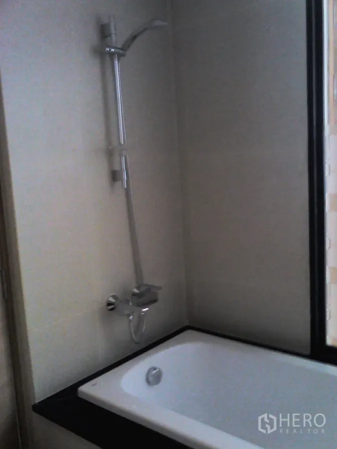 Condominium for rent or sale in Watthana, Bangkok - Modern bathroom with built-in bathtub and handheld shower beside a window in an Ekkamai-area condo.