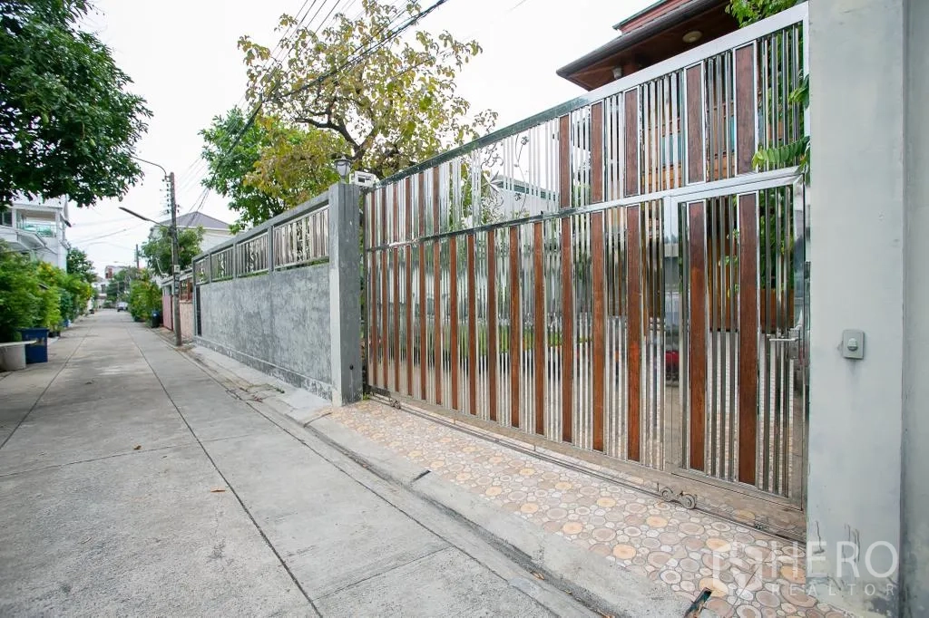 独栋房屋 for rent or sale in Huai Khwang, Bangkok - 宁静小巷一侧的钢与木组合推拉大门入口。