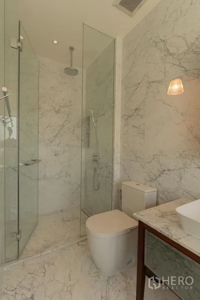 Condominium for rent in Watthana, Bangkok - Bathroom finished in marble with glass rain shower, modern toilet and countertop basin.