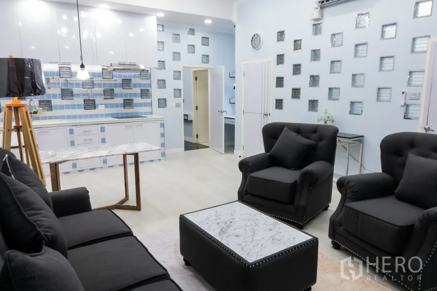 Condominium for rent or sale in Khlong Toei, Bangkok - Spacious open‑plan living area with pendant lights and glass‑block accent walls.