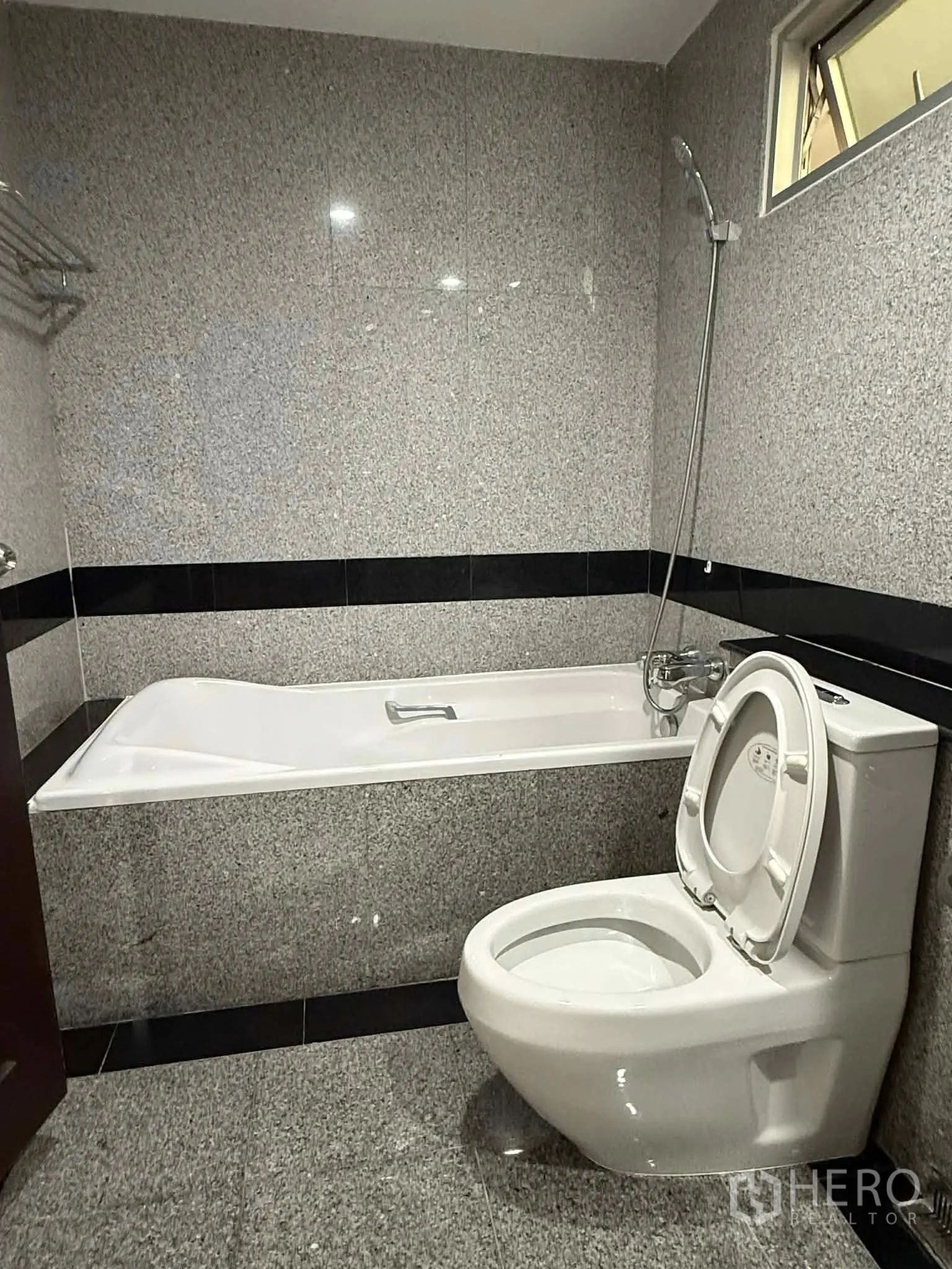 Condominium for rent in Pathum Wan, Bangkok - Bathroom with bathtub, toilet, and granite wall tiles.