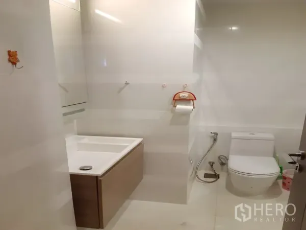 Condominium for sale in Khlong Toei, Bangkok - Modern bathroom with floating vanity, toilet and handheld bidet in neutral tones.