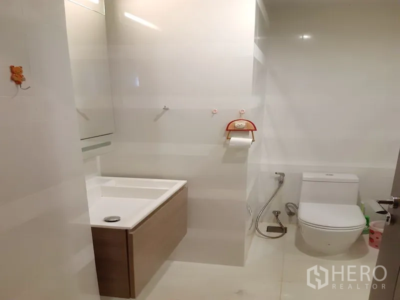 Condominium for sale in Khlong Toei, Bangkok - Modern bathroom with floating vanity, toilet and handheld bidet in neutral tones.