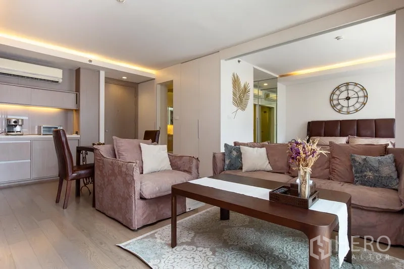 公寓 出租在Watthana, Bangkok - 舒适客厅区，沙发与茶几，厨房旁的镜面墙