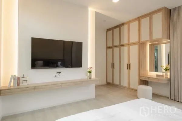 Detached House for rent in Saphan Sung, Bangkok - Primary bedroom with wall-mounted TV, floating console, and full-height wardrobes.