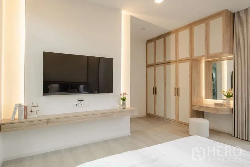 Detached House for rent in Saphan Sung, Bangkok - Primary bedroom with wall-mounted TV, floating console, and full-height wardrobes.