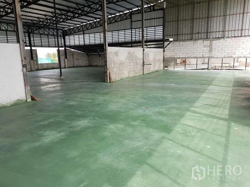 Warehouse for sale in Lam Luk Ka, Pathum Thani - Open-plan warehouse interior with green epoxy flooring, block walls and ample ventilation.