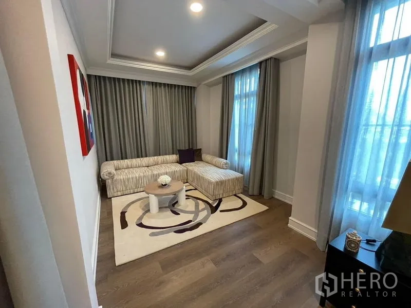 Detached House for rent or sale in Saphan Sung, Bangkok - Private sitting room with L-shaped sofa, layered curtains and recessed ceiling lights.