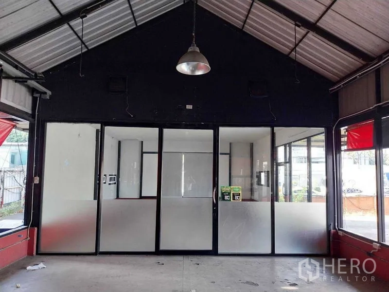 Retail Space for rent in Khlong Toei, Bangkok - High-ceiling retail unit with frosted glass partitions, pendant light, concrete floor, and street-facing windows in Khlong Toei.