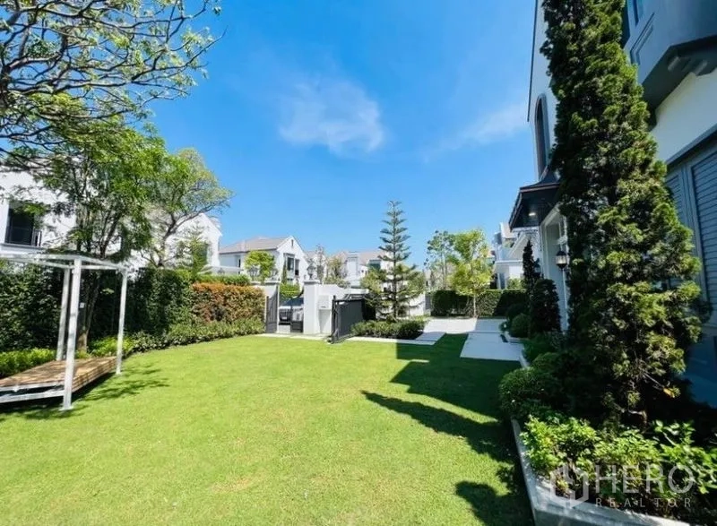 Detached House for rent or sale in Saphan Sung, Bangkok - Spacious private yard with trimmed grass, trees, and walkway beside the home.