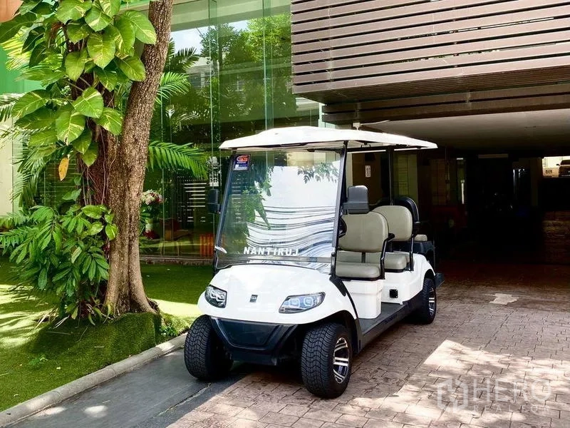 Condominium for rent in Khlong Toei, Bangkok - Electric shuttle golf cart parked by the lobby surrounded by greenery.