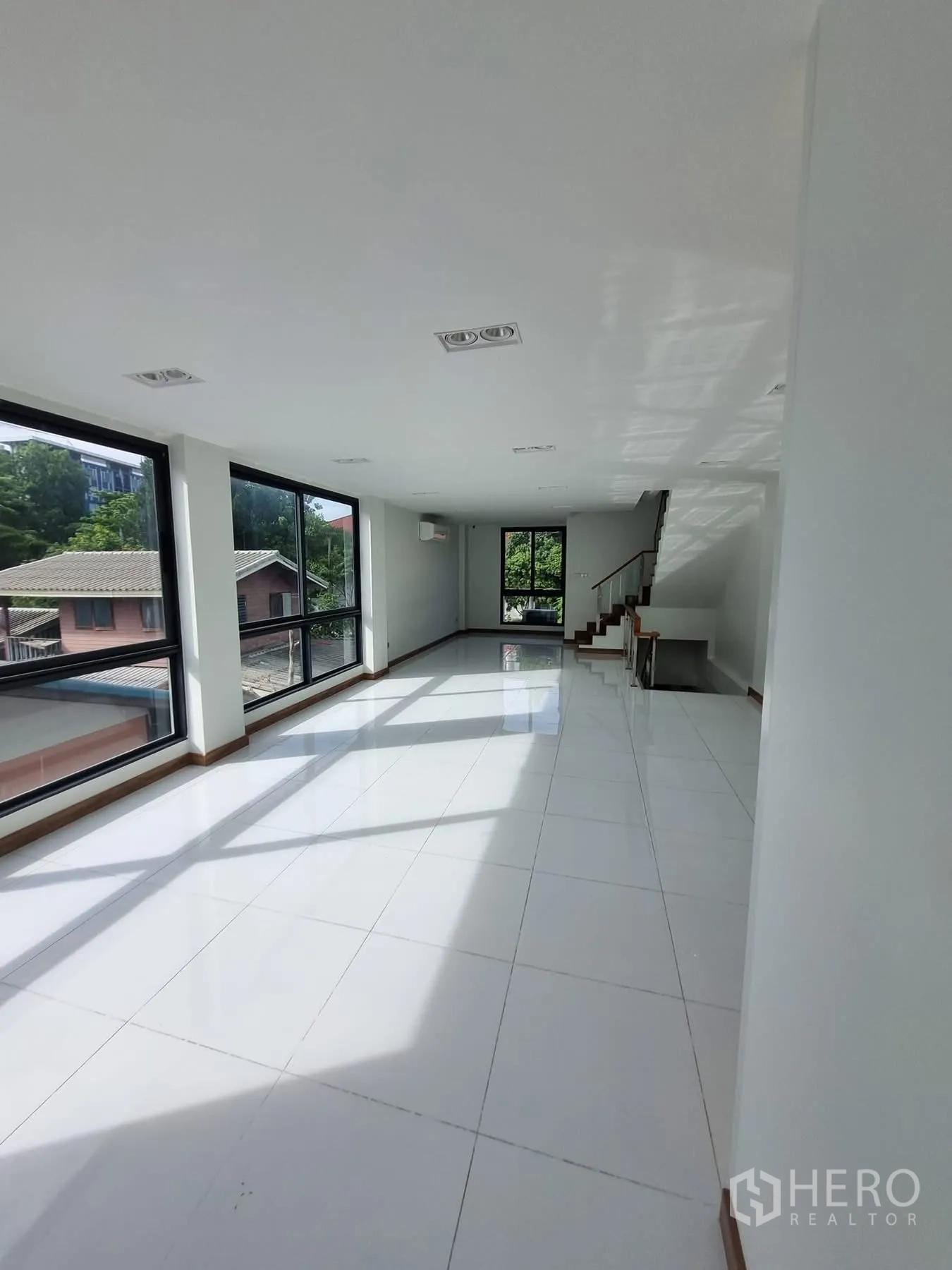 Home Office for rent in Khlong Toei, Bangkok - Long open showroom or office floor with bright white tiles and windows.