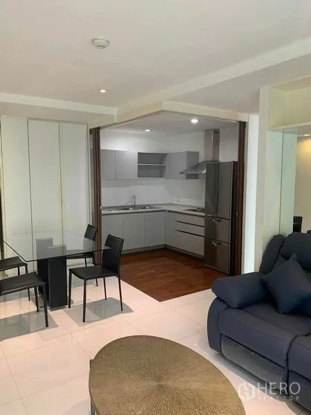 Condominium for rent or sale in Khlong Toei, Bangkok - Living room looking into a modern L-shaped kitchen.