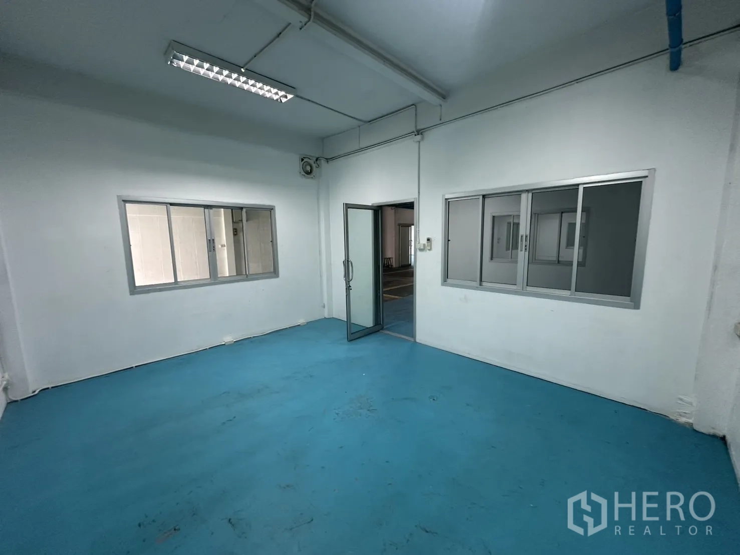 Warehouse for rent in Bang Na, Bangkok - Office space with blue epoxy floor, sliding windows and ceiling lights.