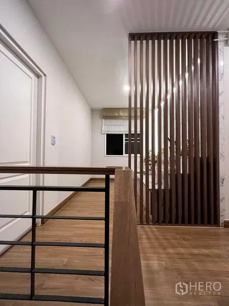 独立式住宅 出租或出售在Lat Krabang, Bangkok - 二层走廊，木格栅隔断与木地板护栏。