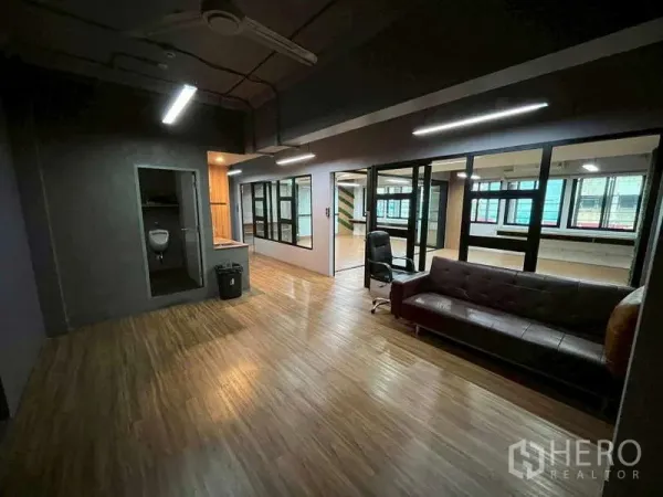 办公空间 出租在Samphanthawong, Bangkok - 现代办公室休闲区，木纹地板、玻璃隔断、沙发与独立卫生间角落。