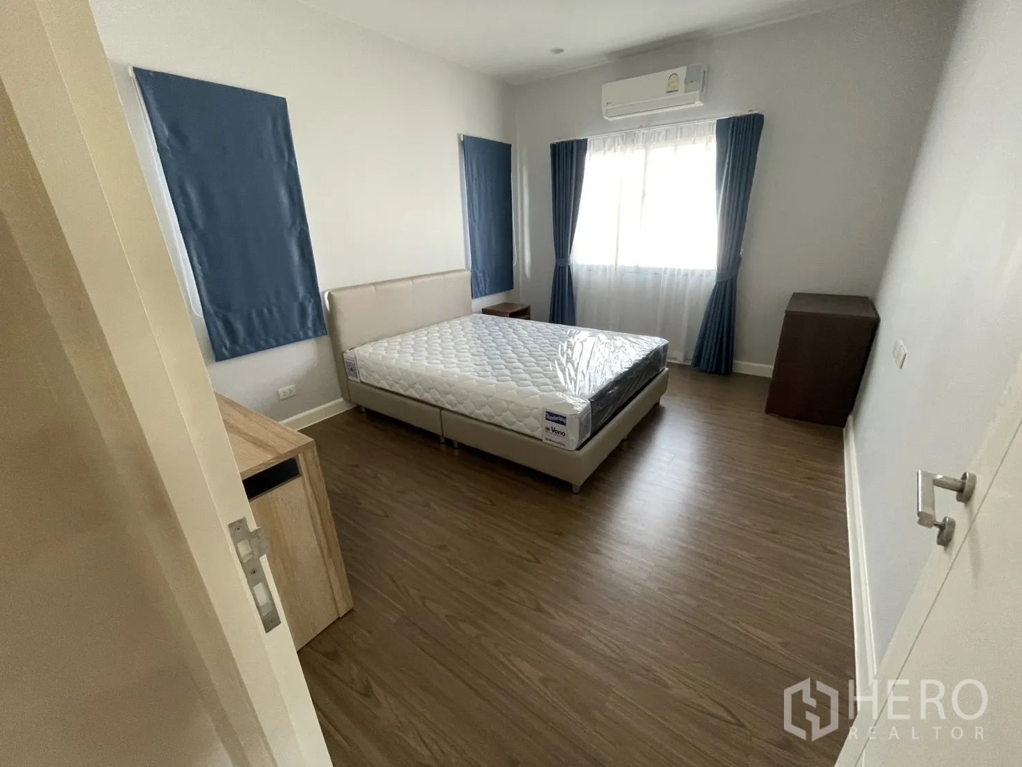 Detached House for rent or sale in Lam Luk Ka, Pathum Thani - Bedroom with new mattress and bed frame, curtains, air-conditioner and wood-look flooring.