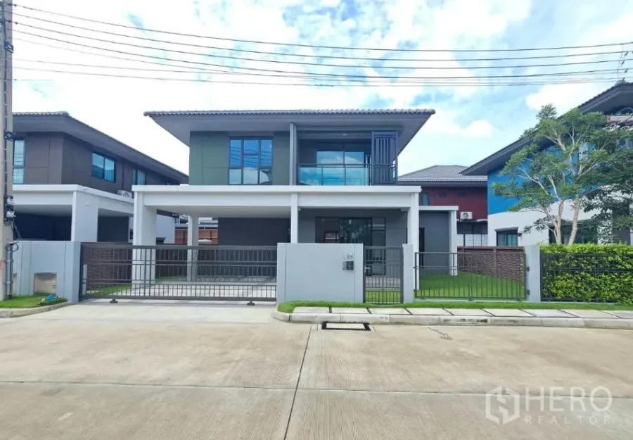 Detached House for sale in Lam Luk Ka, Pathum Thani - Modern two-storey detached house exterior with gated driveway and lawn in Lam Luk Ka.