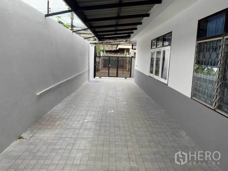 独立式住宅 出租在Huai Khwang, Bangkok - 房屋侧边带顶棚的铺砖车道与铁门车位。