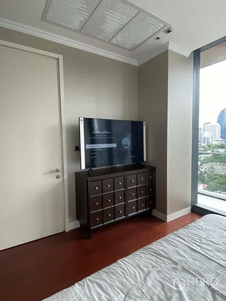 公寓 出租在Watthana, Bangkok - 卧室一角，电视柜与大窗户框景城市。