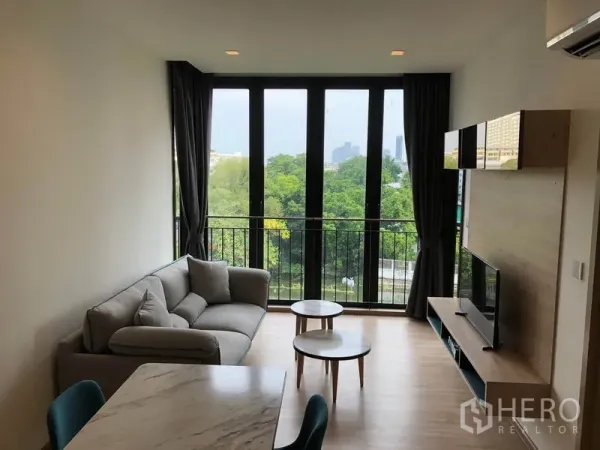 公寓 出租在Watthana, Bangkok - Kawa Haus客厅，落地窗与阳台，绿景与河渠景，配沙发、电视与茶几。