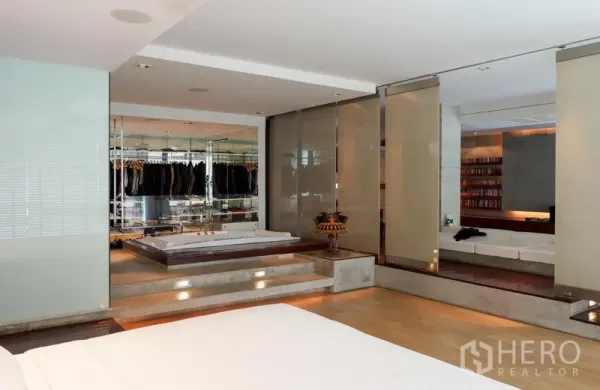 Condominium for rent or sale in Khlong Toei, Bangkok - Primary suite with raised platform, mirrored wardrobes and connection to lounge area.