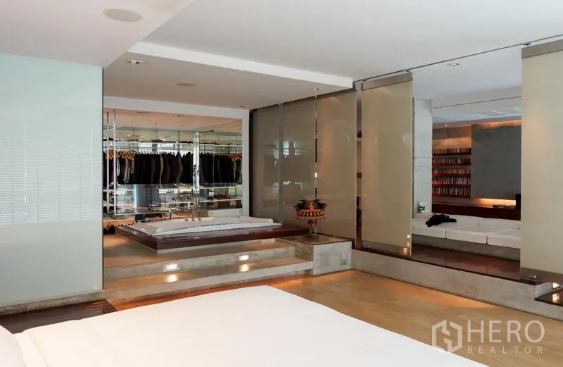 Condominium for rent or sale in Khlong Toei, Bangkok - Primary suite with raised platform, mirrored wardrobes and connection to lounge area.