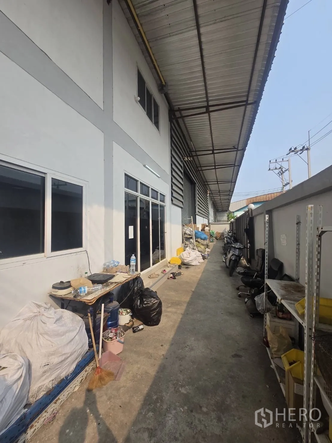 โรงงาน for rent or sale in Mueang Samut Sakhon, Samut Sakhon - ทางเดินด้านข้างมีหลังคาคลุม ติดหน้าต่างอาคารและชั้นวางของ