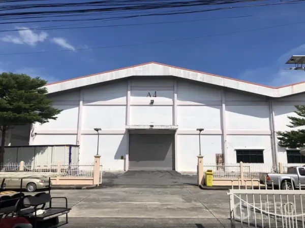 货栈 出租 - 白色人字顶仓库外立面，中央A4卷闸门与坡道，封闭园区内，蓝天下。