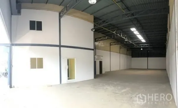 货栈 出租在Pak Kret, Nonthaburi - 高挑钢结构仓库内部，带采光板和白色隔出的办公区。