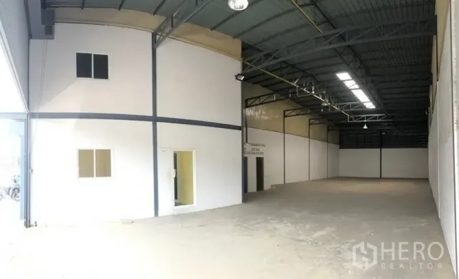 货栈 出租在Pak Kret, Nonthaburi - 高挑钢结构仓库内部，带采光板和白色隔出的办公区。