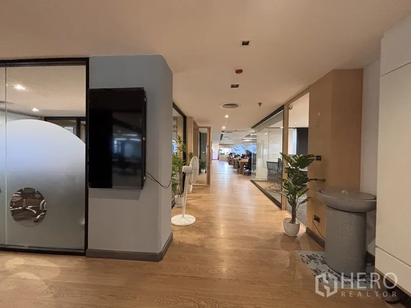 Office Space for rent in Bang Rak, Bangkok - Hallway with indoor plants and glass partitions opening to offices and meeting rooms.