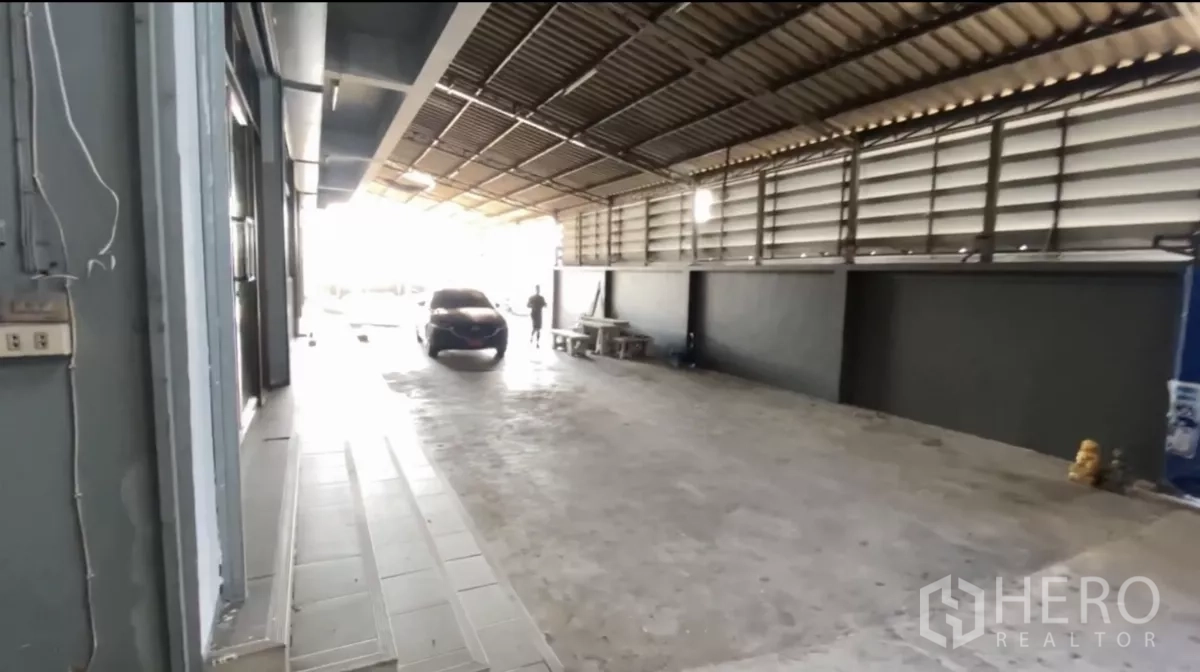 Factory for rent in Bang Phli, Samut Prakan - Sheltered car park and service lane under a metal roof beside the office façade.