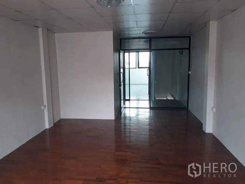 Townhouse for sale in Bang Kapi, Bangkok - Spacious room with polished wood floor and glass partitioned office area.
