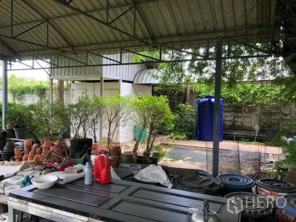 Warehouse for rent in Bang Bua Thong, Nonthaburi - Covered outdoor work area with benches, potted plants and utility water tank.