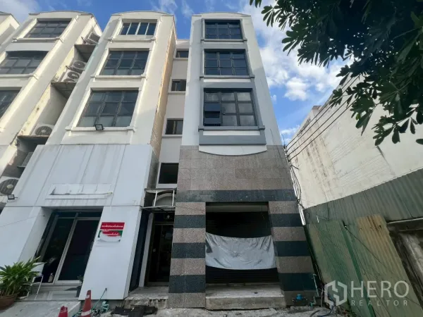 Shophouse for rent in Phra Khanong, Bangkok - Four-storey shophouse facade with wide windows and roller shutter entrance.